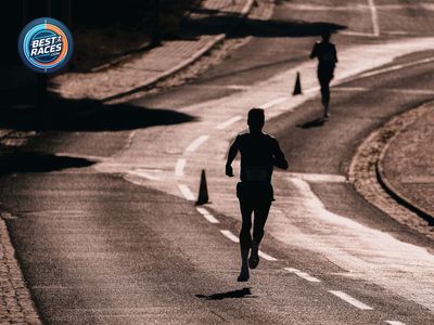 Two runners casting long shadows on a closed race course