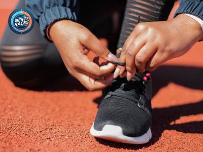 A runner lacing up her shoes trackside before a workout