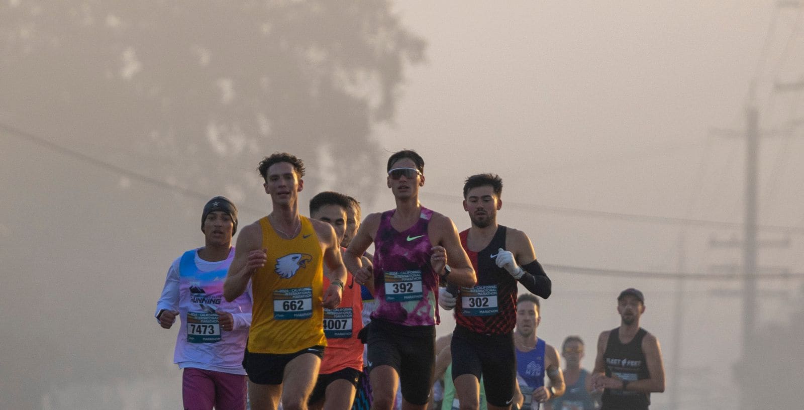 A tight chase pack of club runners racing a foggy morning road race